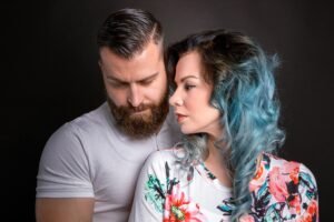 A couple embracing in a studio setting with a gray background, showcasing intimacy and style.