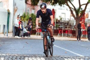 Focused male cyclist riding through the city street during a competitive race event.