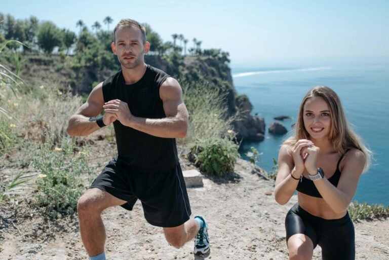 A couple performs fitness exercises on a cliff with a scenic sea view, promoting healthy living.